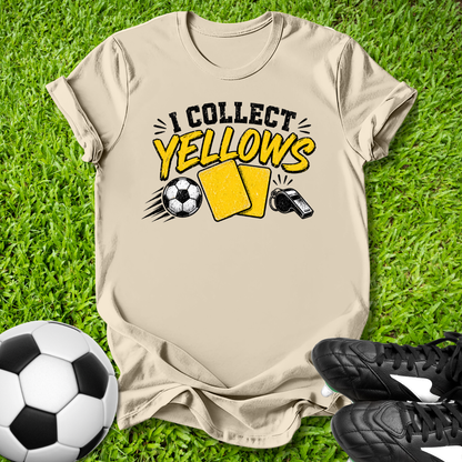 Beige t-shirt with 'I Collect yellows' text and soccer ball graphics on grass with soccer ball and shoes.
