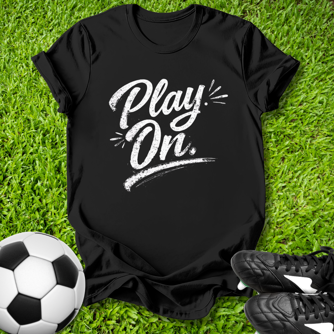 Black t-shirt with 'Play On' text on grass with soccer ball and shoes