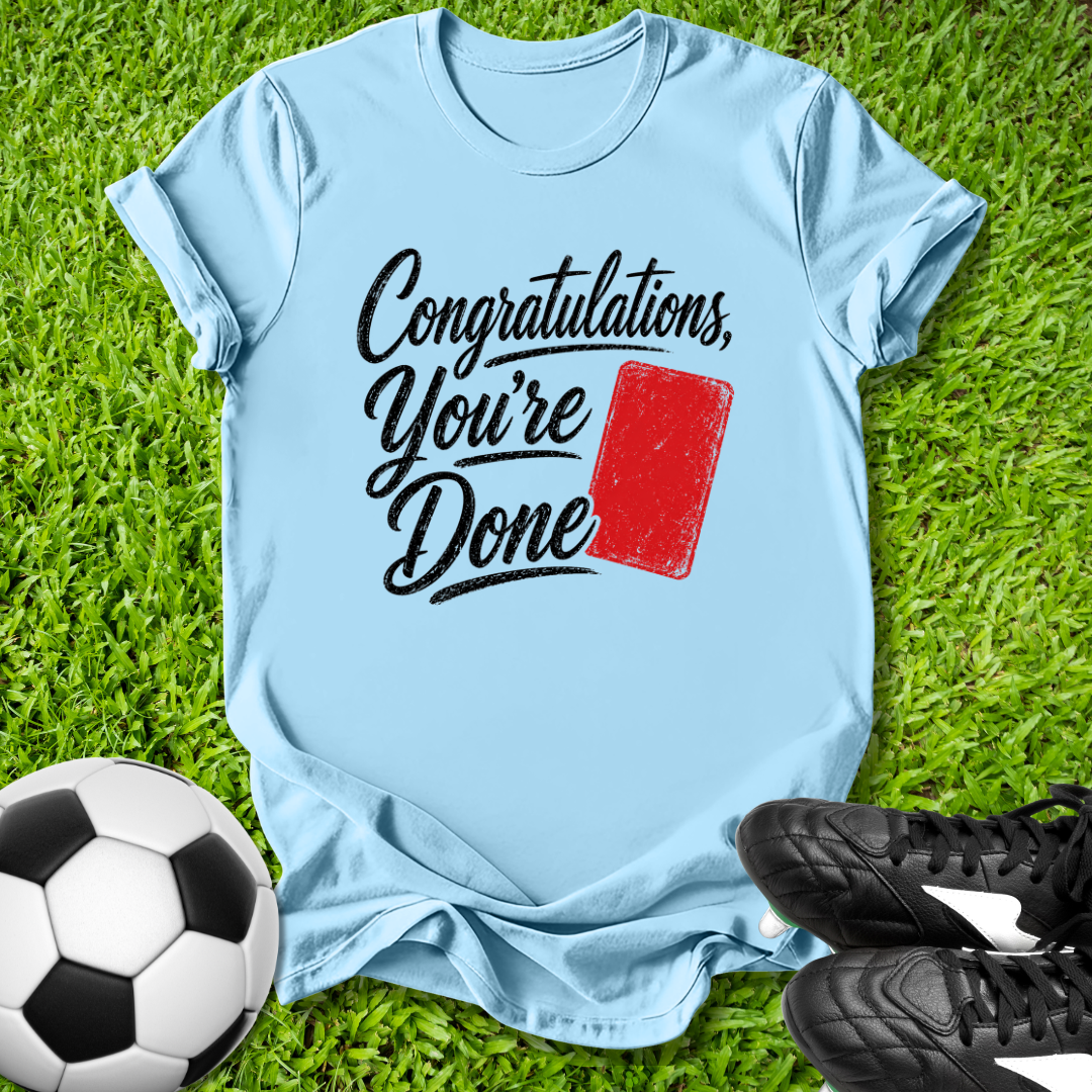 Light blue t-shirt with 'Congratulations, You're Done' text and red card on grass with soccer ball and shoes.