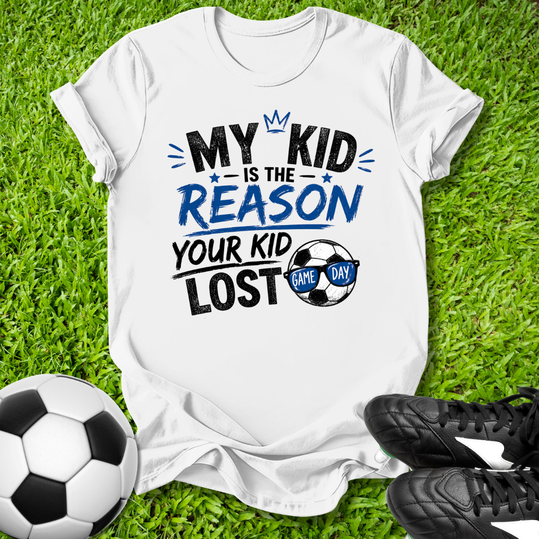 White  t-shirt with humorous My Kid is the Reason Your Kid Lost text soccer-themed text on grass with soccer ball and shoes.