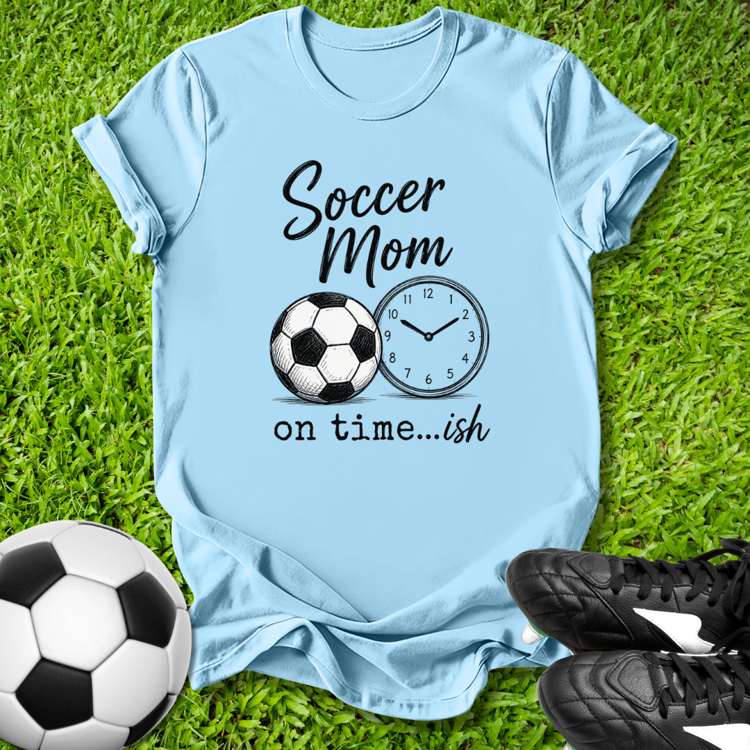 Light blue t-shirt with 'Soccer Mom on time...ish' text and soccer ball graphic on grass with soccer ball and shoes.