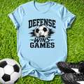 Light blue t-shirt with 'Defense Wins Games' text and soccer ball graphic on grass, with soccer ball and shoes.