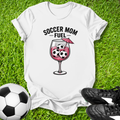 White t-shirt with 'Soccer Mom Fuel' design on grass with soccer ball and cleats.
