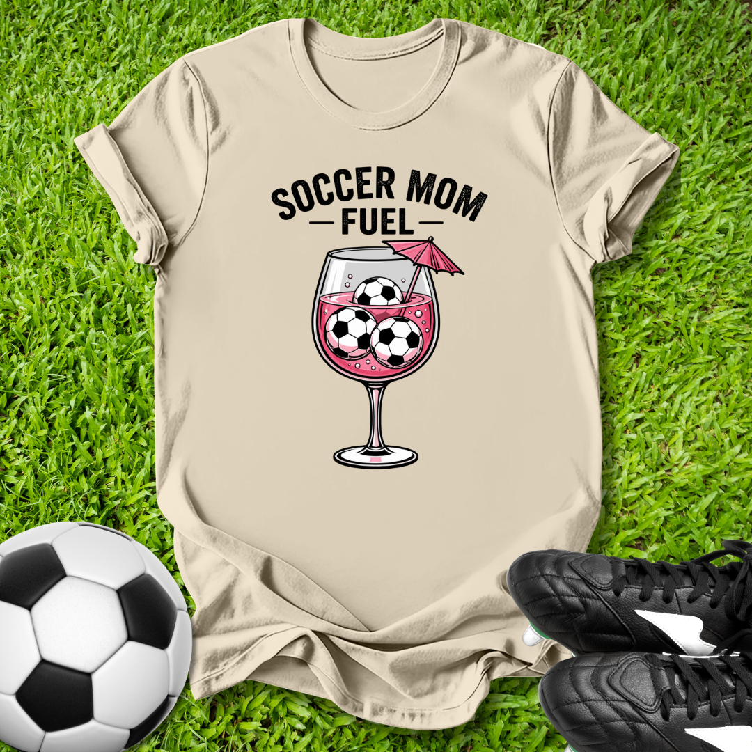 Beige t-shirt with 'Soccer Mom Fuel' graphic on grass with soccer ball and cleats.
