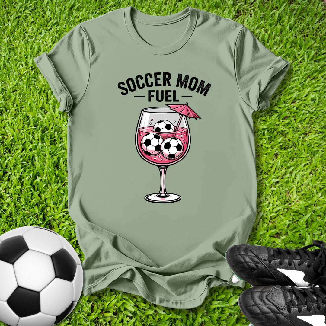 Green t-shirt with 'Soccer Mom Fuel' graphic on grass with soccer ball and shoes.