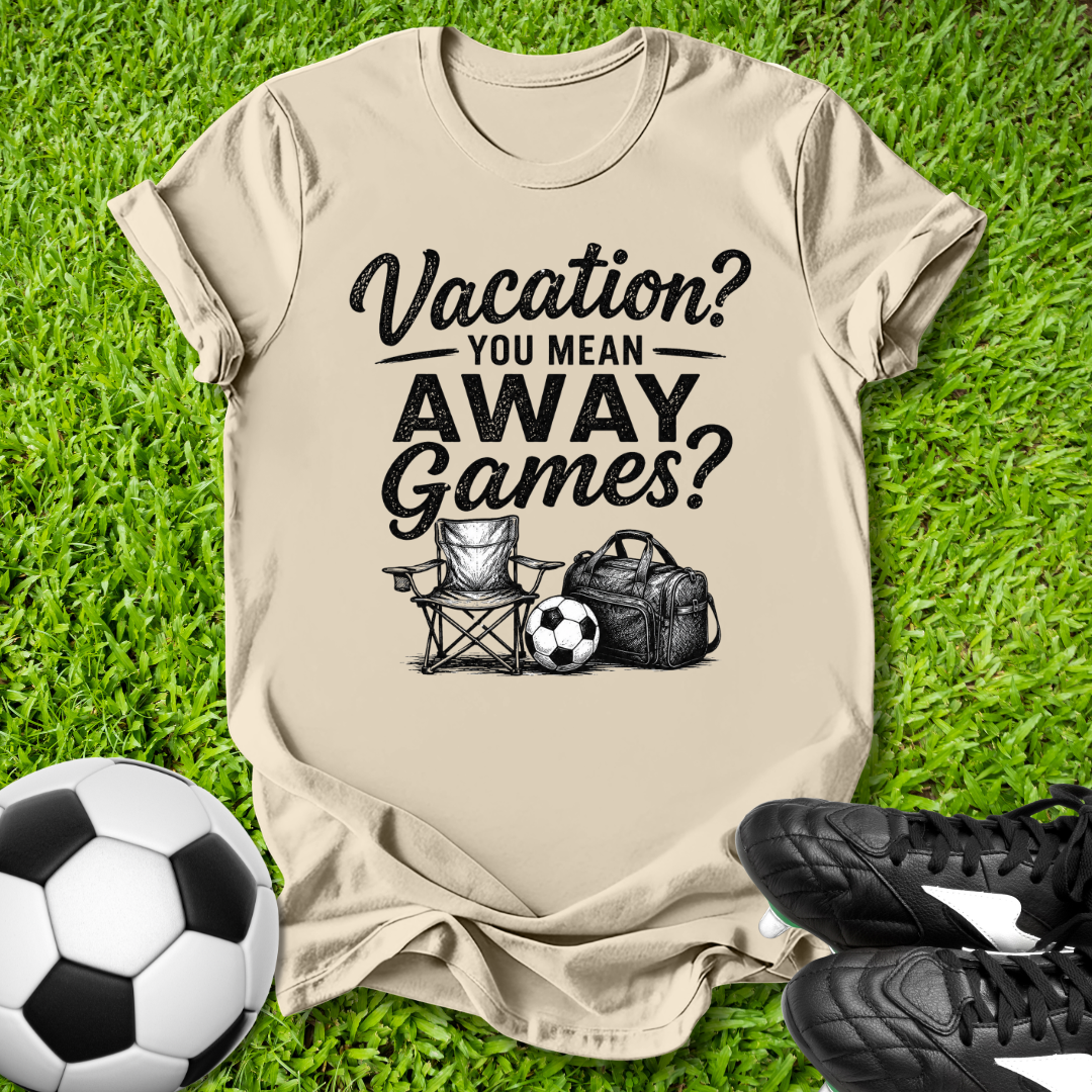 Beige t-shirt with 'Vacation? You Mean Away Games?' text and graphics on grass with soccer ball and shoes.