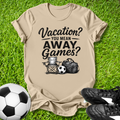 Beige t-shirt with 'Vacation? You Mean Away Games?' text on grass with soccer ball and shoes.