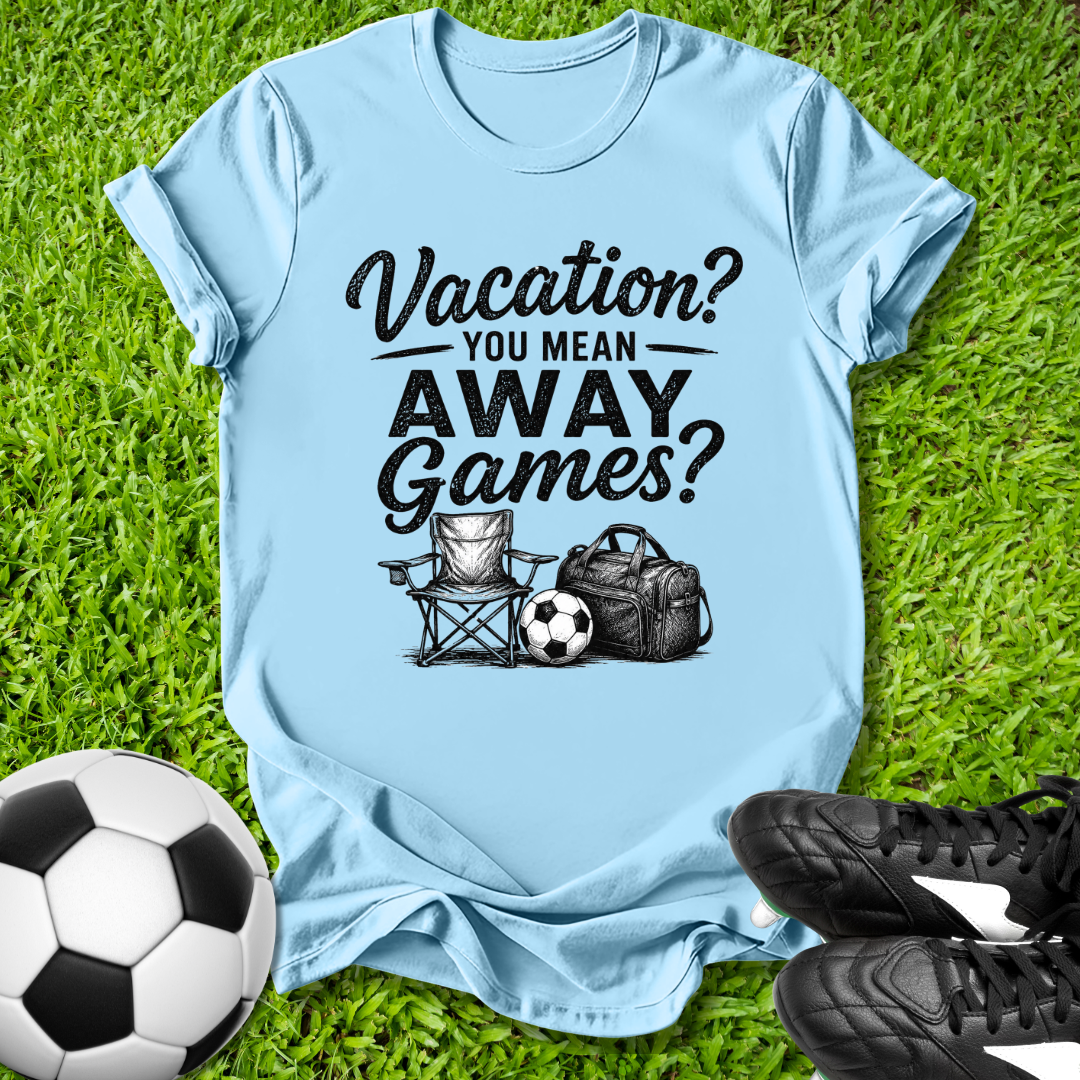 Light blue t-shirt with 'Vacation? You mean AWAY Games?' text on grass with soccer ball and shoes.