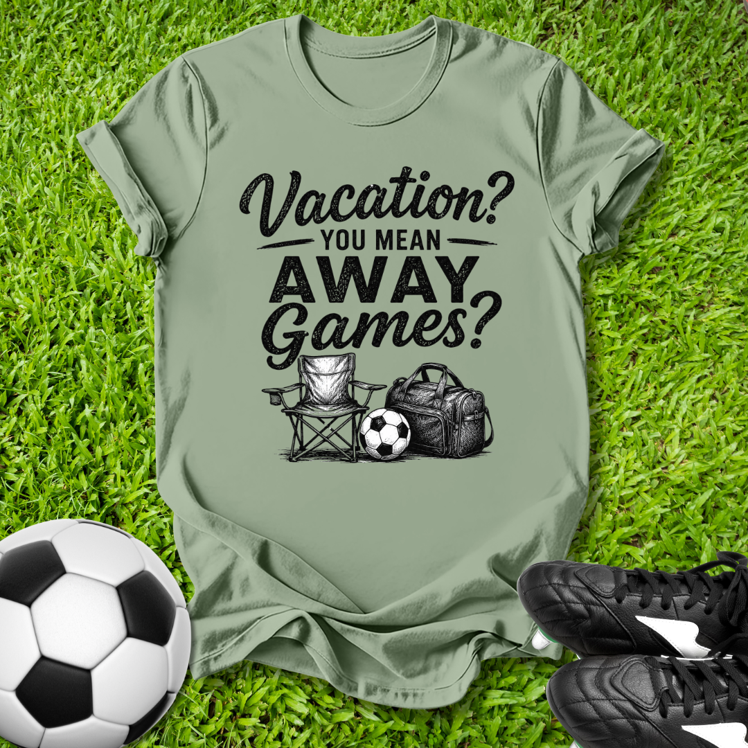 Green t-shirt with 'Vacation? You mean AWAY Games?' text on grass with soccer ball and shoes.