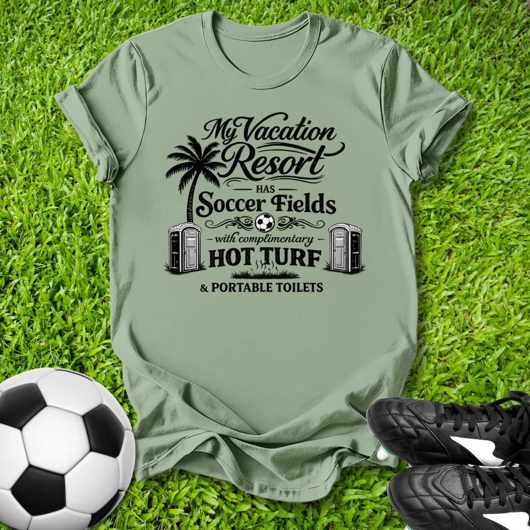 Green t-shirt with a humorous graphic and text on grass with soccer ball and shoes.