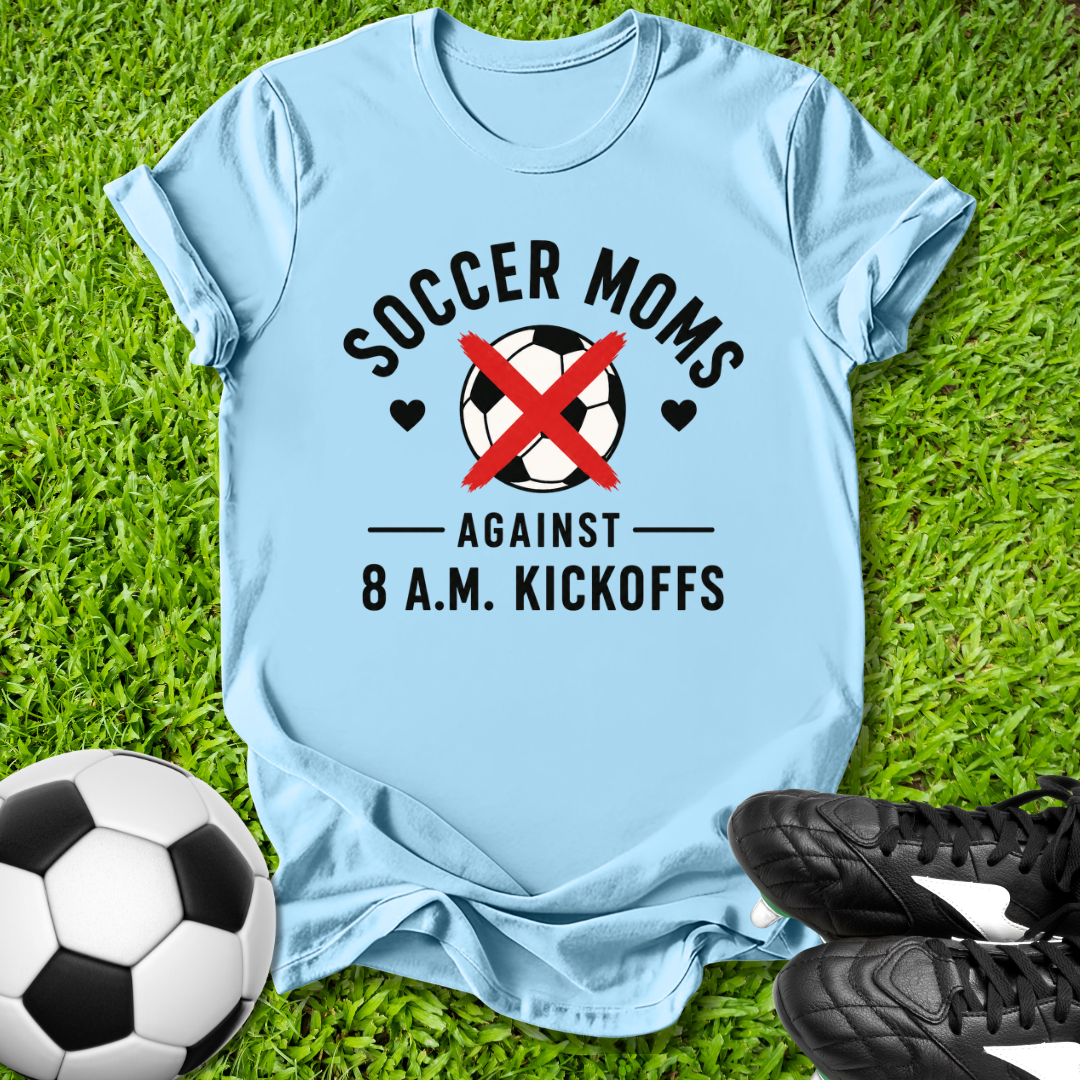 Light t-shirt with 'Soccer Moms Against 8 A.M. Kickoffs' design on grass with soccer ball and shoes.
