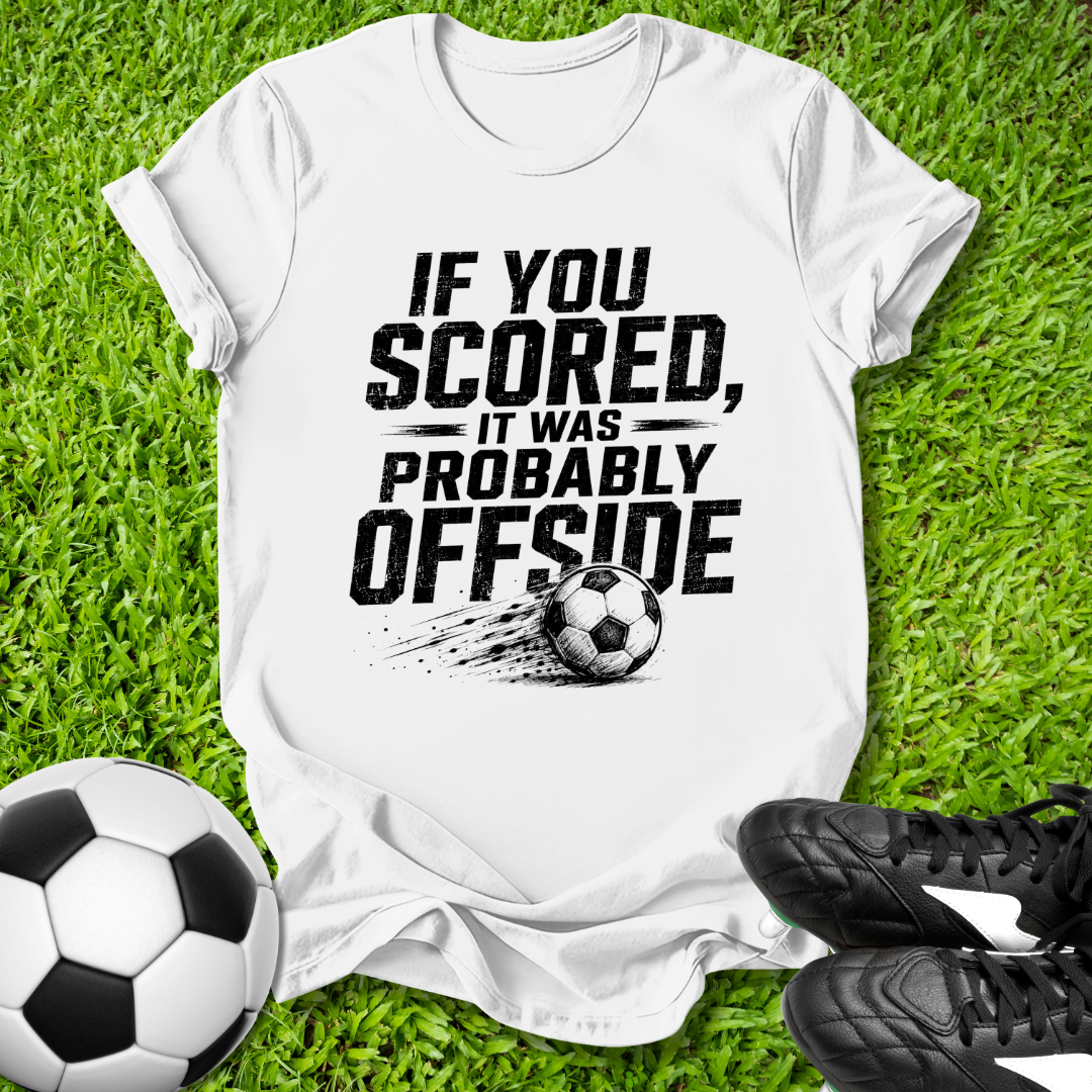 White t-shirt with offside soccer-themed text on grass with soccer ball and cleats