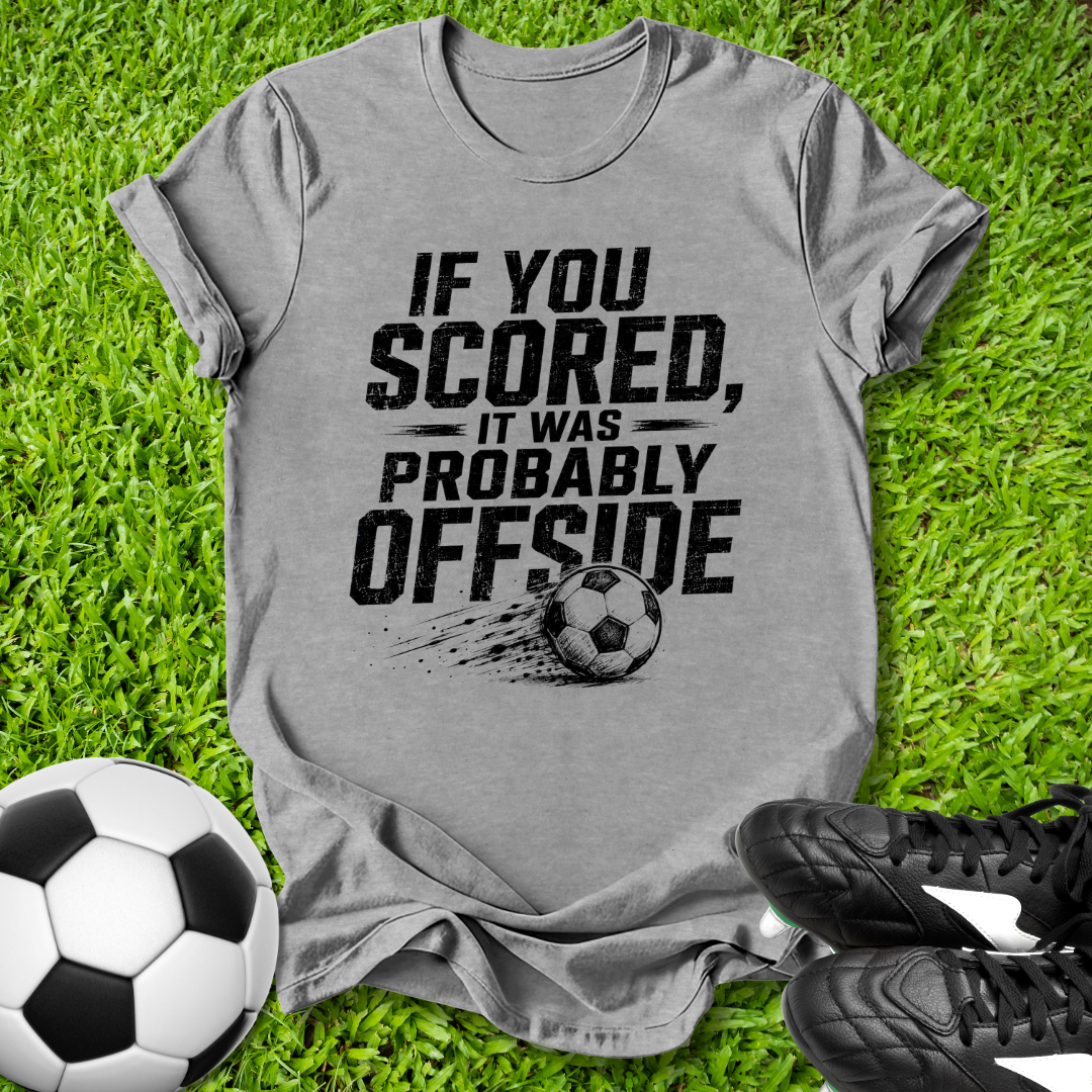 Gray t-shirt with offside soccer-themed text on grass with soccer balls and shoes.