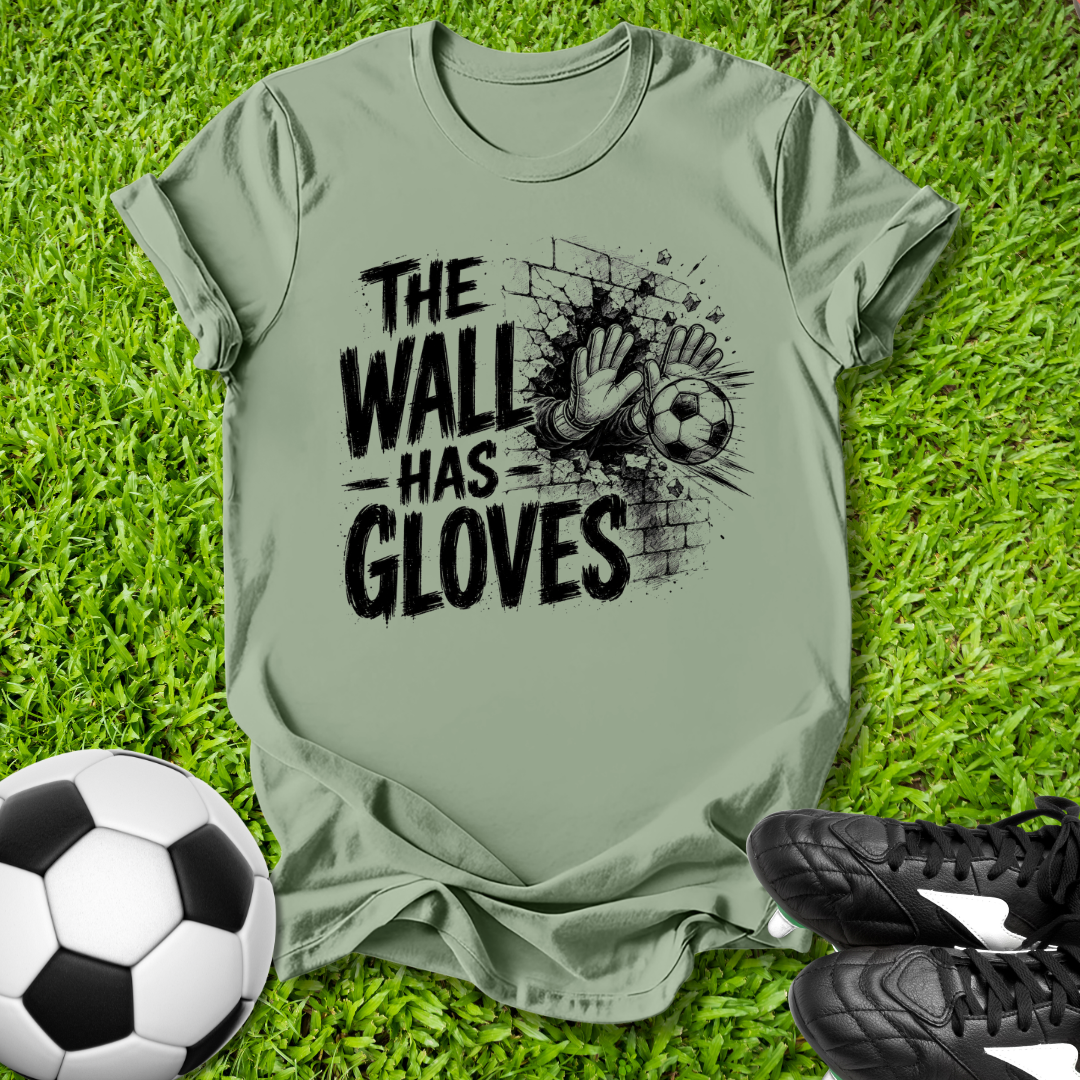 Green t-shirt with 'The Wall Has Gloves' graphic on grass with soccer ball and shoes.