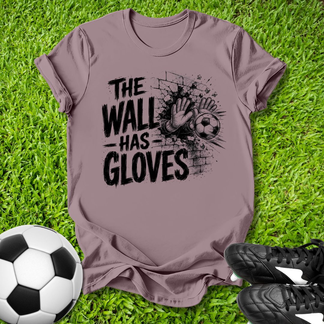 Purple t-shirt with 'The Wall Has Gloves' graphic on grass with soccer ball and shoes.