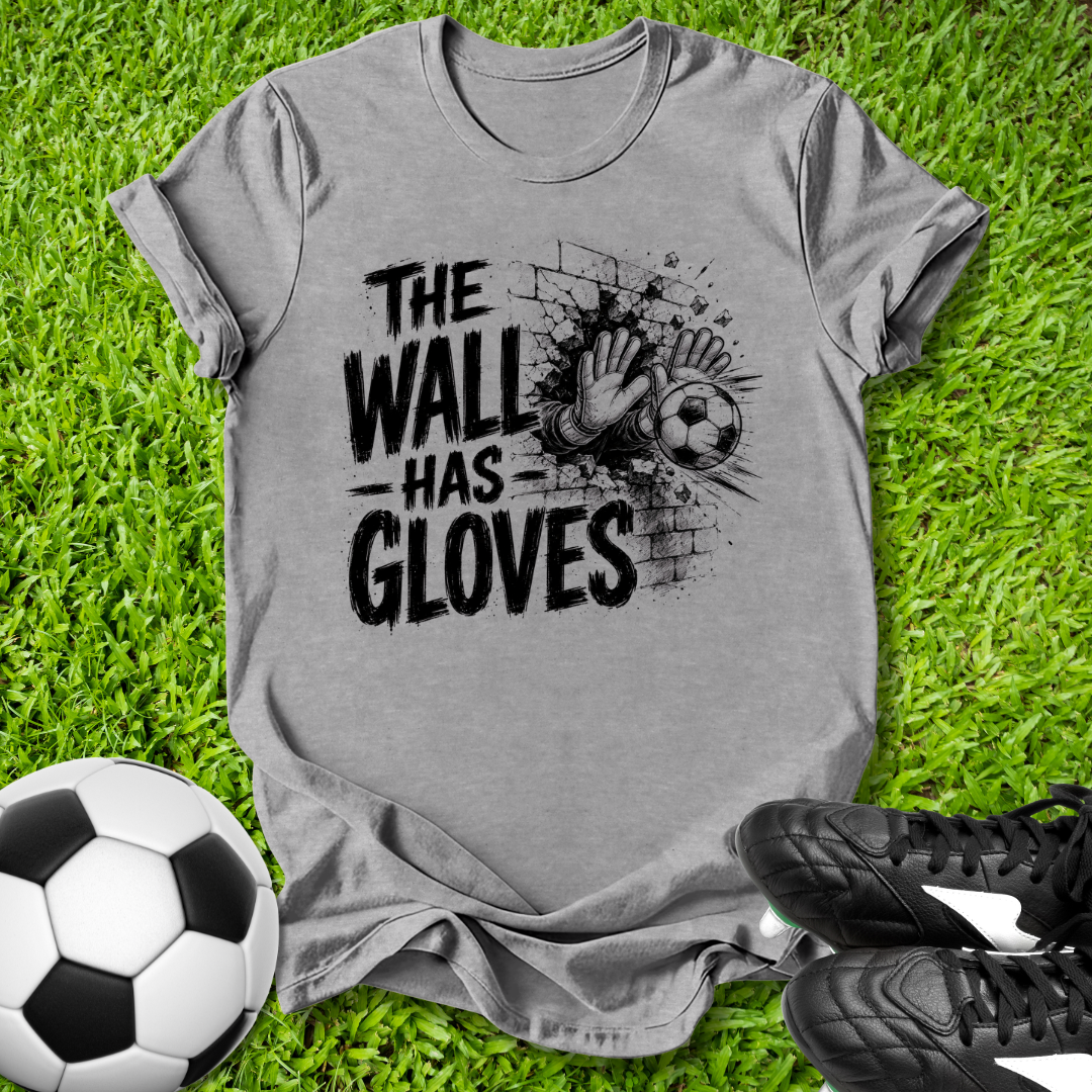Gray t-shirt with 'The Wall Has Gloves' graphic on grass with soccer ball and shoes.