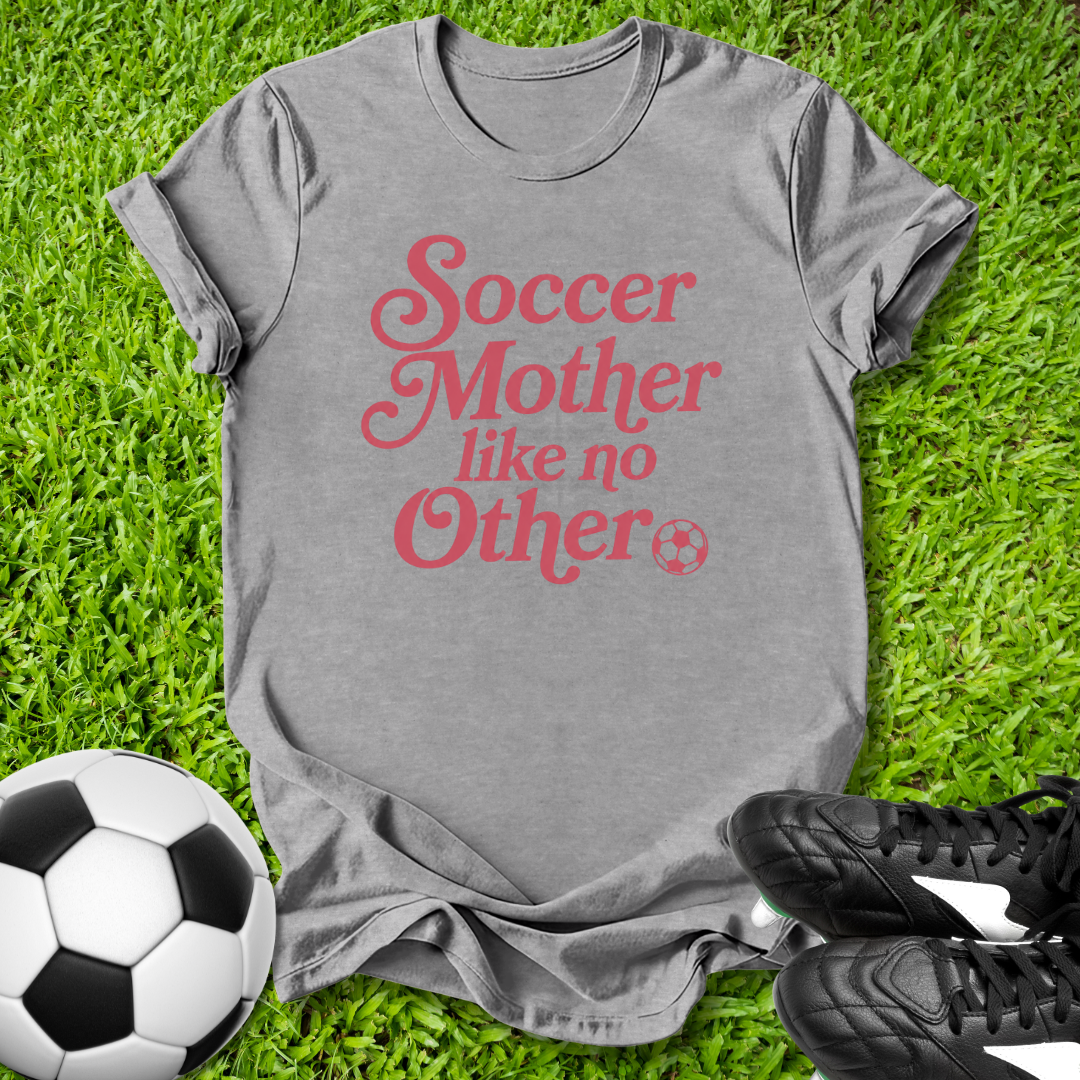 Gray t-shirt with 'Soccer Mother like no Other' text on grass with soccer ball and shoes.