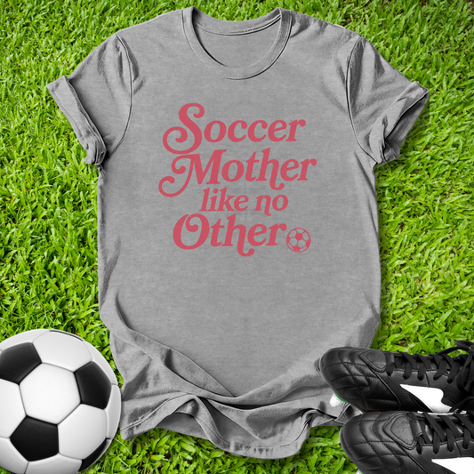Gray t-shirt with 'Soccer Mother like no Other' text on grass with soccer ball and shoes.