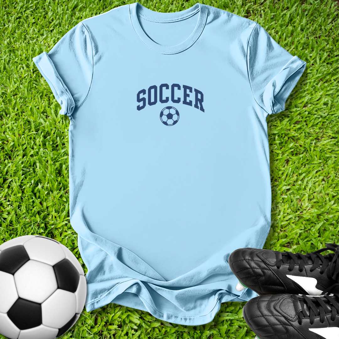 Light blue t-shirt with 'SOCCER' text and soccer ball graphic on grass, with soccer ball and shoes.