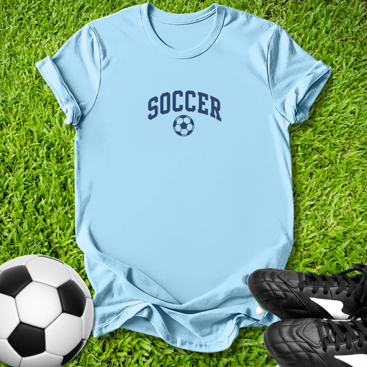 Light blue t-shirt with 'SOCCER' text and soccer ball graphic on grass, with soccer ball and shoes.