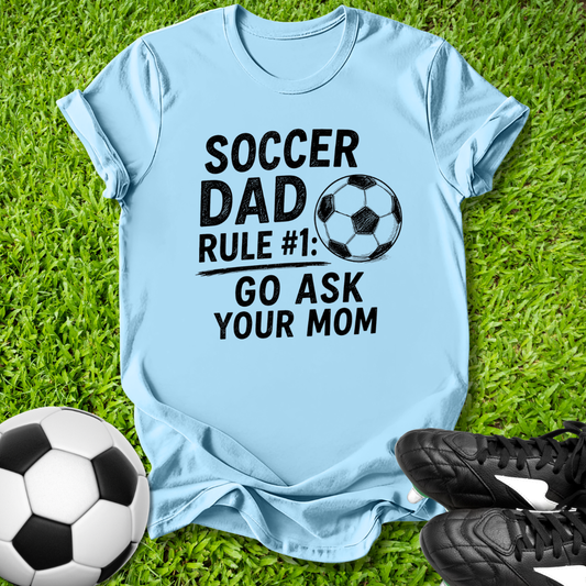 Light blue t-shirt with 'Soccer Dad Rule #1 go ask your mom' text on grass with soccer ball and shoes