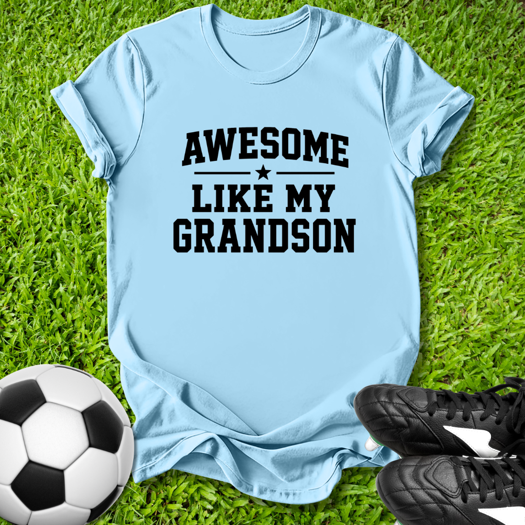 Light blue t-shirt with 'Awesome like my grandson' text on grass with soccer ball and shoes.