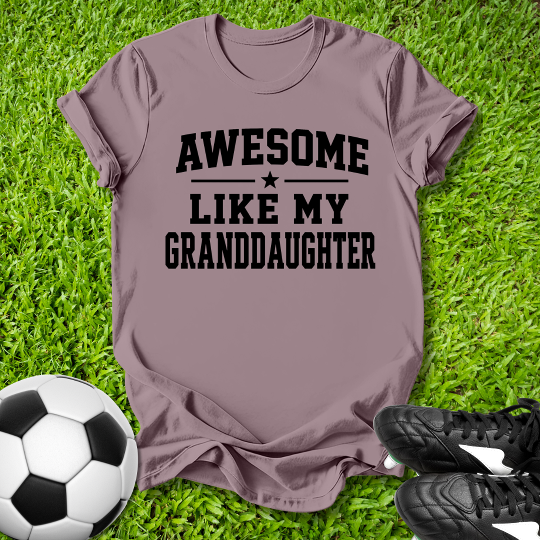 Purple t-shirt with 'Awesome like my granddaughter' text on grass with soccer ball and shoes