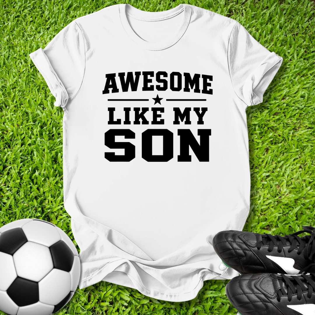 White t-shirt with 'Awesome Like My Son' text on grass with soccer ball and shoes