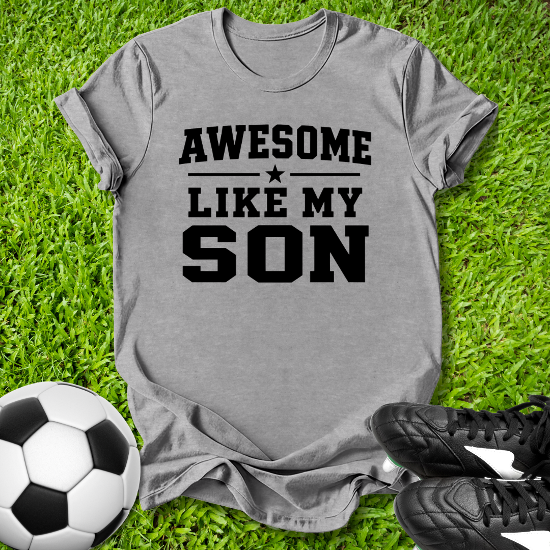 Gray t-shirt with 'Awesome Like My Son' text on grass with soccer ball and shoes.