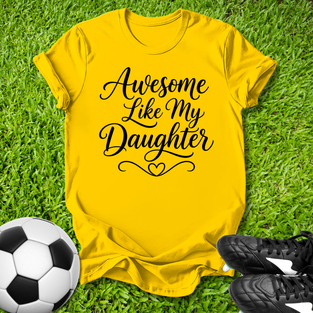 Yellow t-shirt with 'Awesome Like My Daughter' text on grass with soccer ball and shoes.