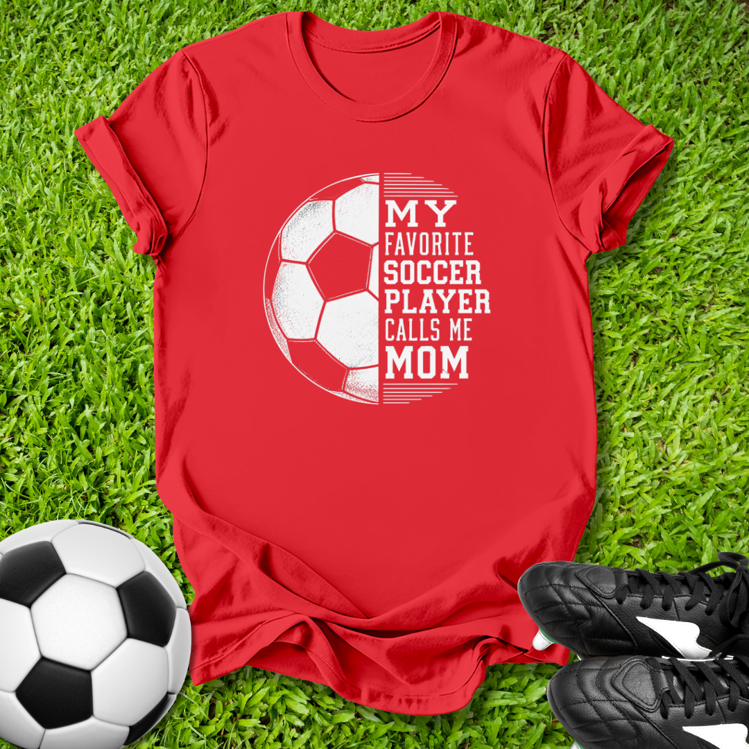 Red t-shirt with soccer design and text on grass with soccer ball and shoes