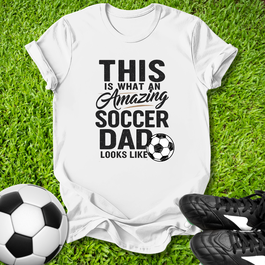 White Light blue t-shirt with 'This is what an amazing soccer dad looks like' text on grass with soccer ball and shoes.