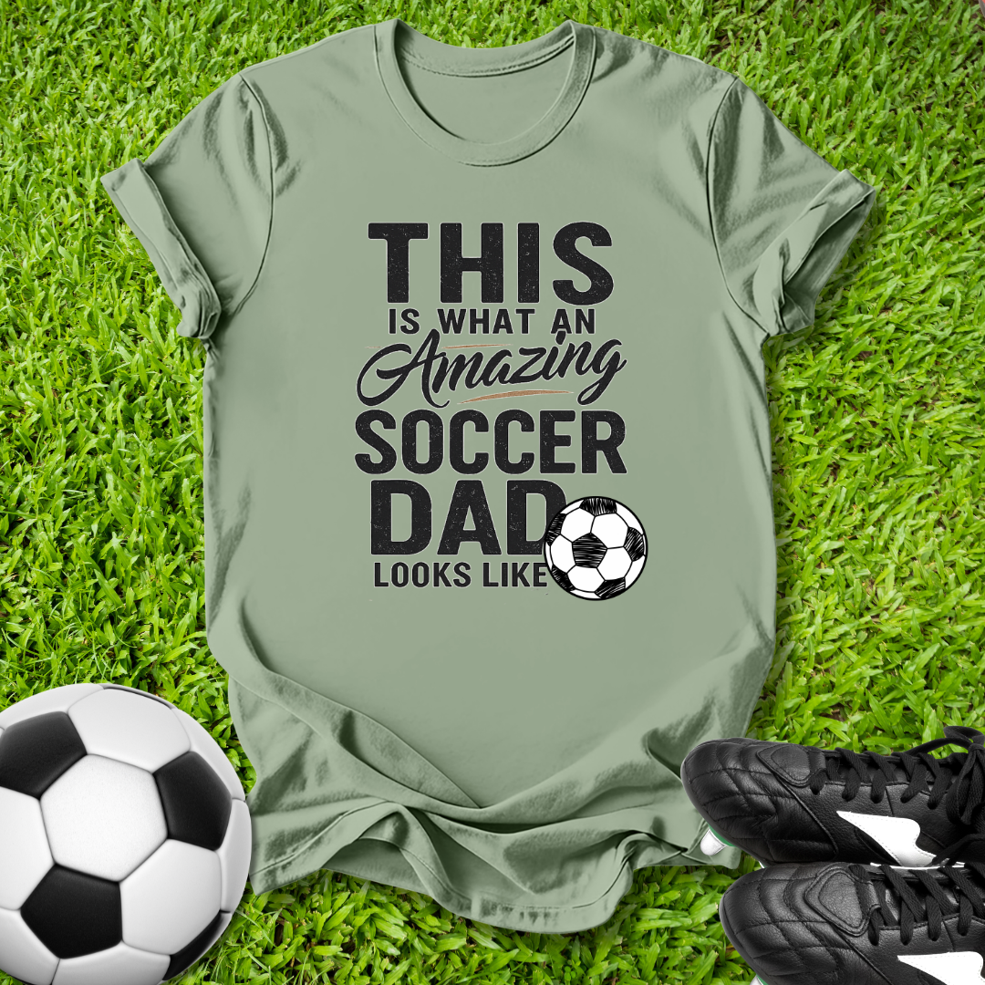 Green Light shirt with 'This is what an amazing soccer dad looks like' text on grass with soccer ball and shoes.