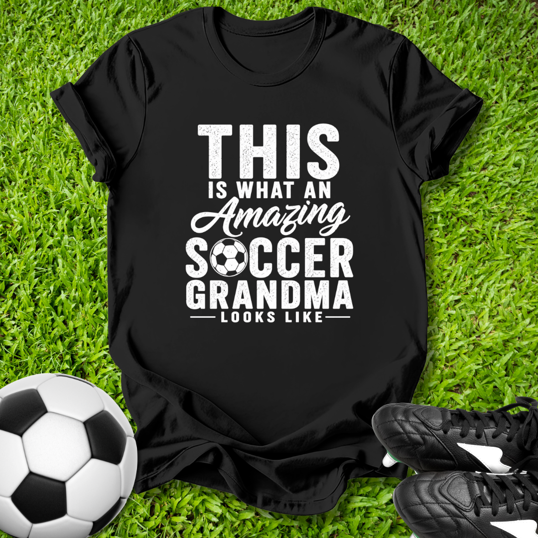 Black t-shirt with 'Amazing Soccer Grandma' text on grass with soccer ball and shoes