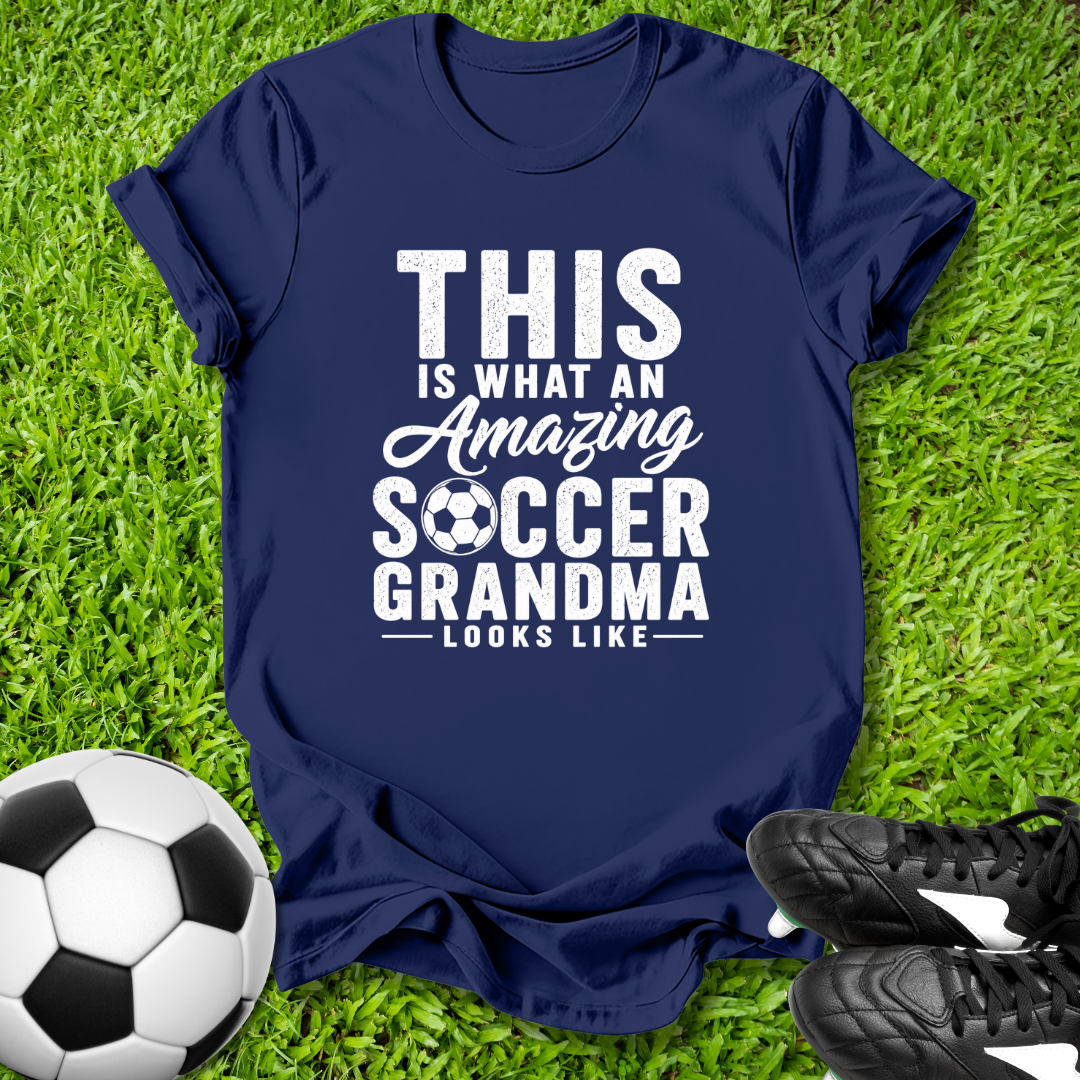 Navy blue t-shirt with 'Amazing Soccer Grandma' text on grass with soccer ball and shoes.