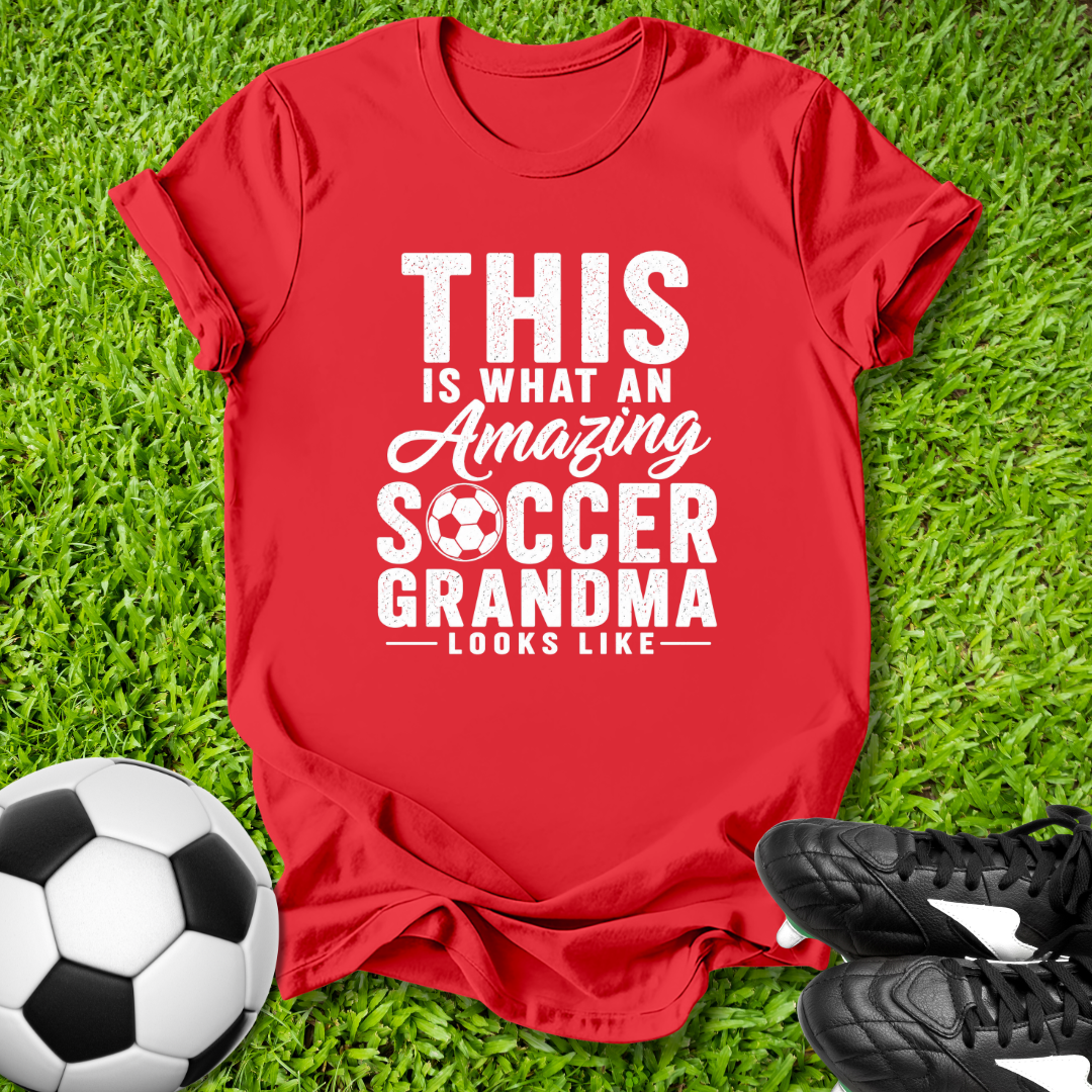 Red t-shirt with 'Amazing Soccer Grandma' text on grass with soccer ball and shoes