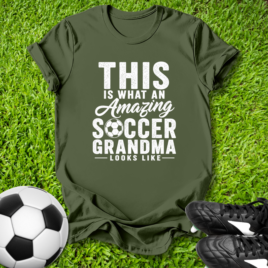 Green t-shirt with 'Amazing Soccer Grandma' text on grass with soccer ball and shoes.