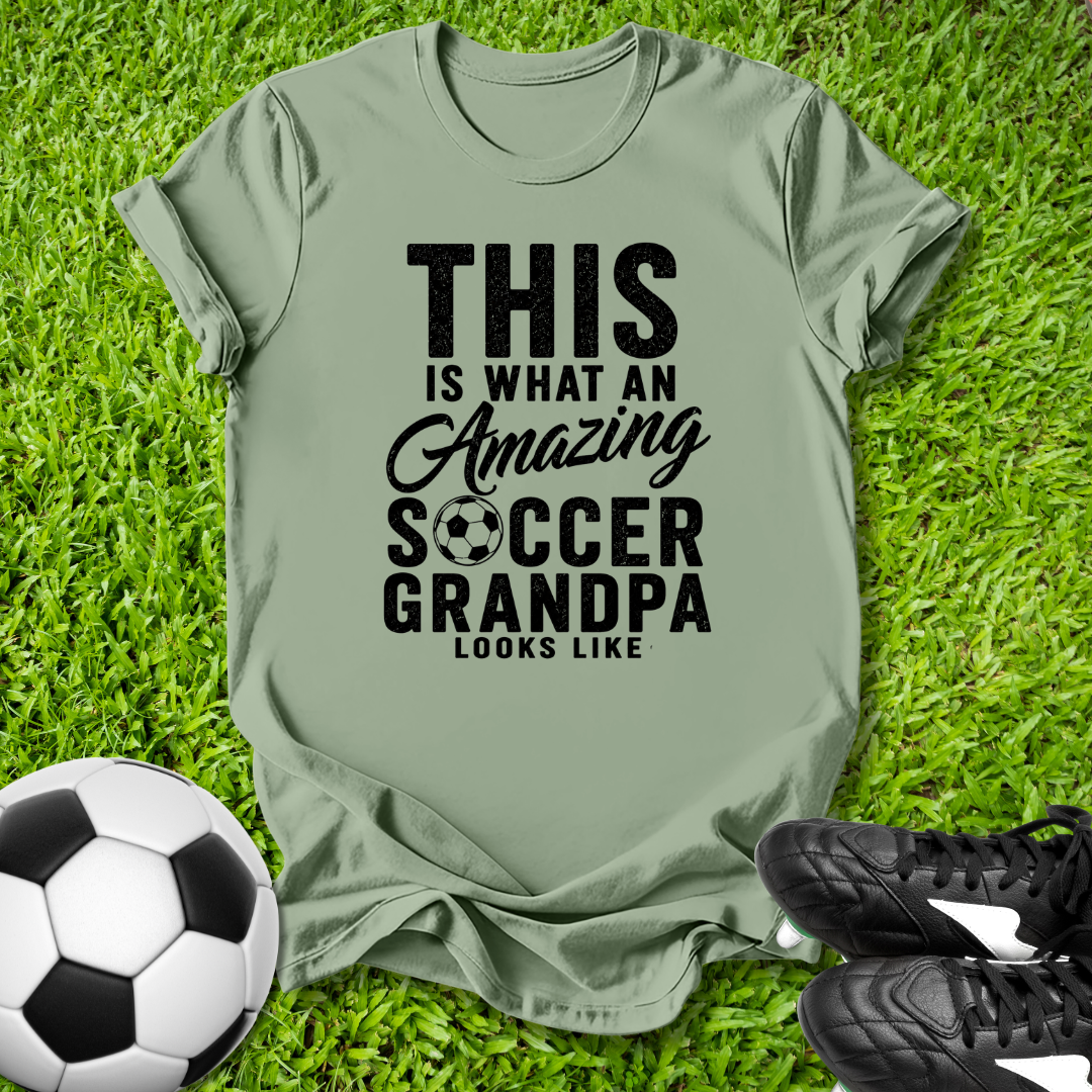 Green t-shirt with 'Amazing Soccer Grandpa' text on grass with soccer ball and shoes