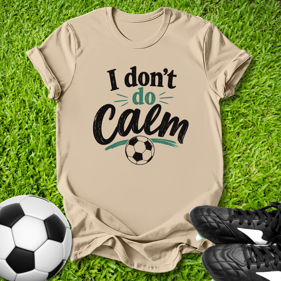 Beige t-shirt with 'I don't do Calm' text on grass with soccer ball and shoes