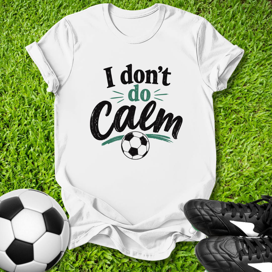 White t-shirt with 'I don't do Calm' text on grass with soccer ball and shoes