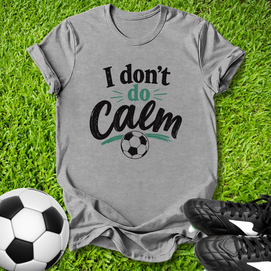 Gray t-shirt with 'I don't do Calm' text on grass with soccer ball and shoes