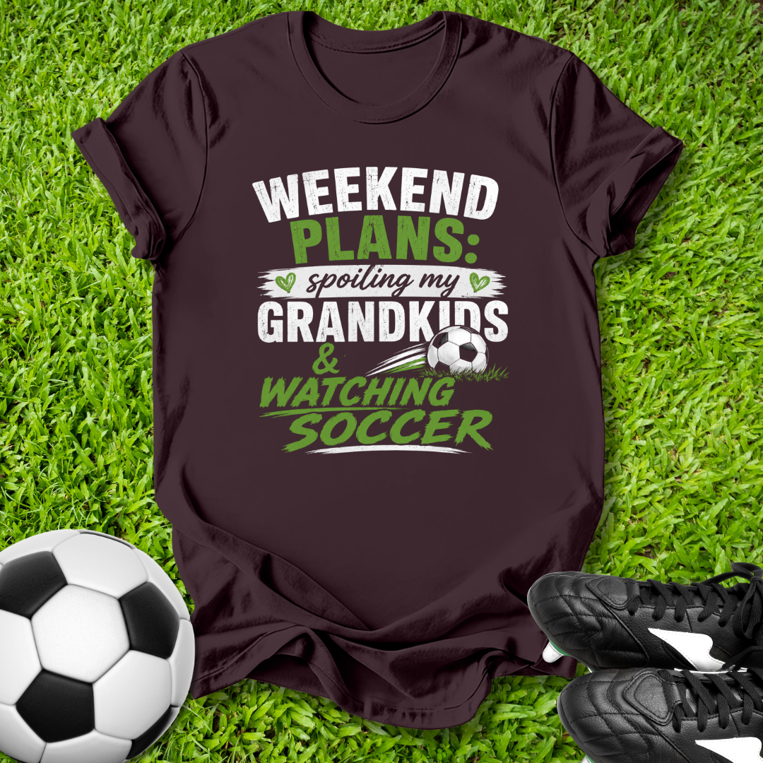 Brown t-shirt with 'Weekend Plans' text on grass with soccer ball and shoes