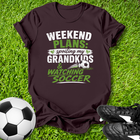 Brown t-shirt with 'Weekend Plans' text on grass with soccer ball and shoes