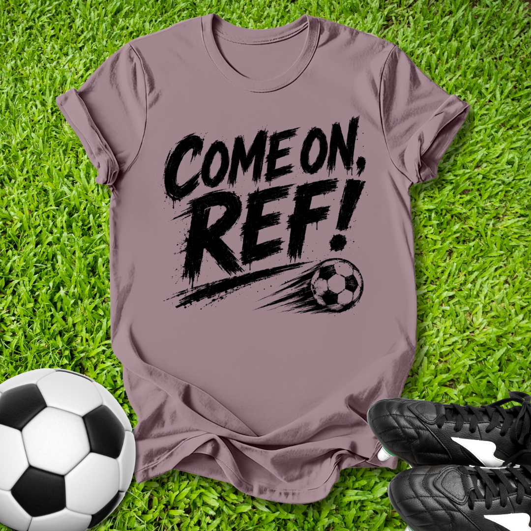 Purple t-shirt with 'COME ON, REF!' text on grass with soccer ball and shoes