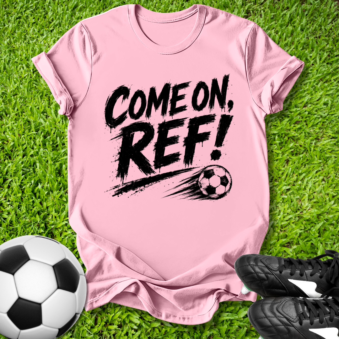 Pink t-shirt with 'COME ON, REF!' text on grass with soccer ball and shoes