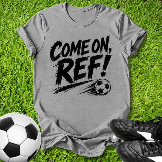 Gray t-shirt with 'COME ON, REF!' text on grass with soccer balls and shoes.