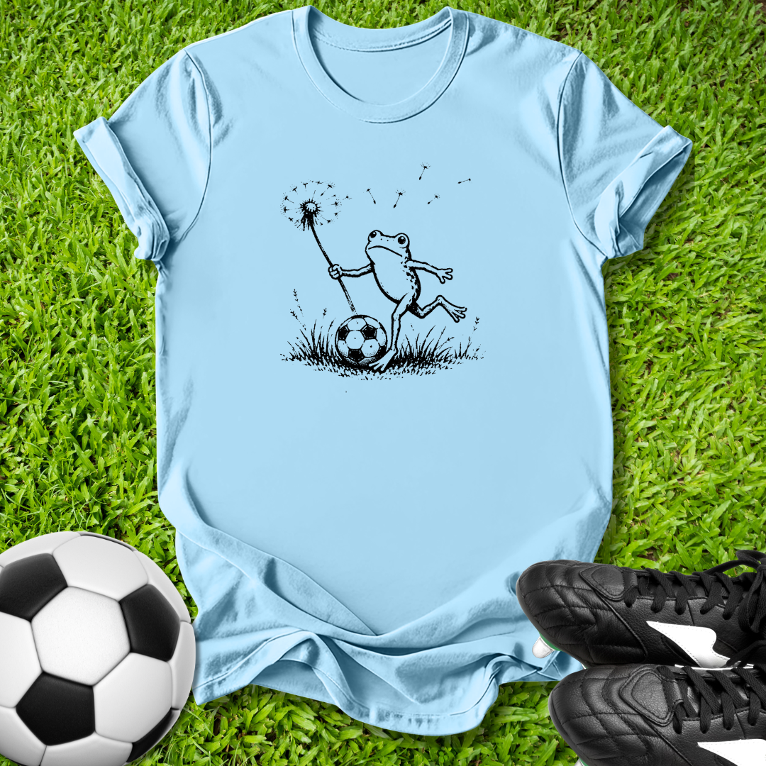 Blue  t-shirt with a frog graphic on grass with soccer ball and shoes