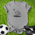 Gray t-shirt with a frog graphic on grass with soccer ball and shoes