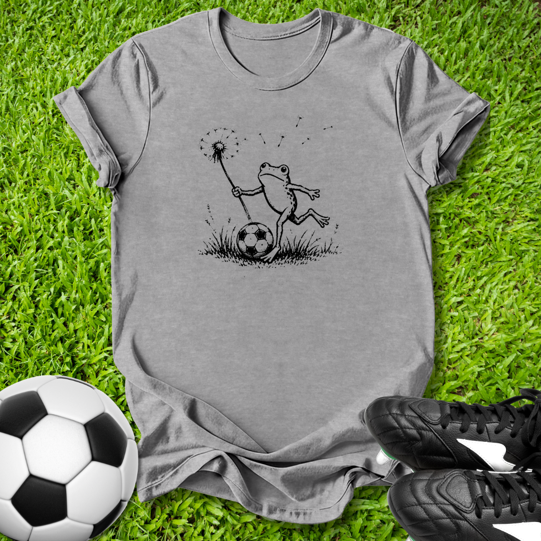 Gray t-shirt with a frog graphic on grass with soccer ball and shoes