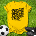 Yellow t-shirt with 'PRESSURE PRESSURE PRESSURE!' text on grass with soccer ball and shoes.